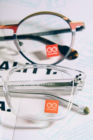 Zwei Brillen mit Markenaufkleber auf einer Textur unter einem Dokument.