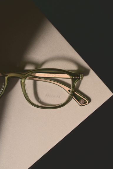 Grüne Brille auf einem neutralen Untergrund in sanften Lichtverhältnissen.