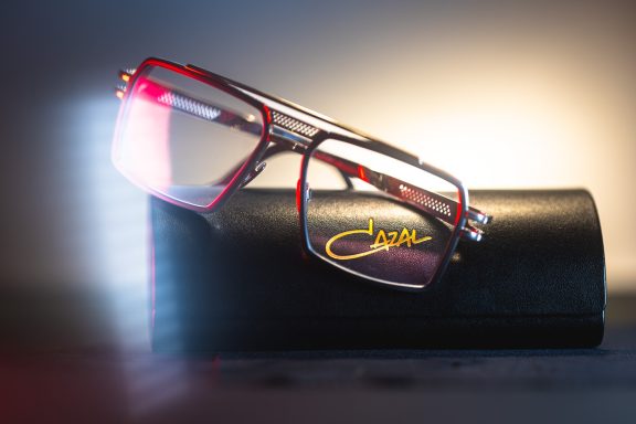 Rote Brille auf einem schwarzen Etui, mit schwachem Licht im Hintergrund.